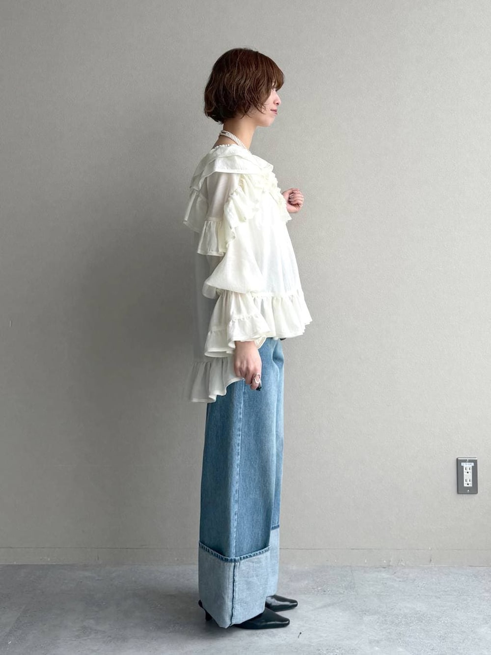 ブラック系のサンダル、ベージュ系のトレンチコート、ブルー系のデニムパンツを着用したレディースの春コーディネートの6枚目の写真