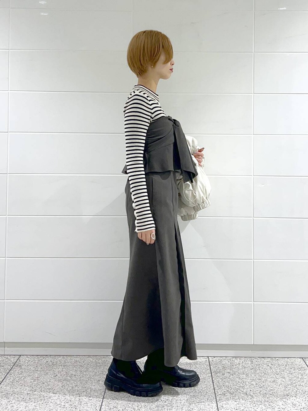 ブラック系のブーツ、ブラック系のニット/セーター、ホワイト系のブルゾンを着用したレディースの冬コーディネートの5枚目の写真