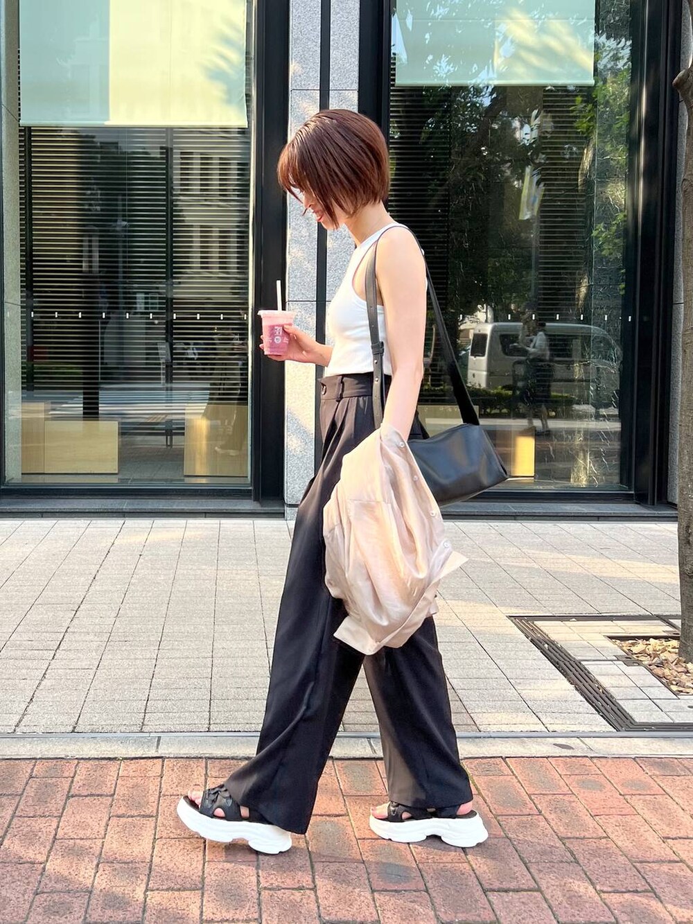 ブラック系のサンダル、ブラック系のスラックス、ブラック系のショルダーバッグを着用したレディースの夏コーディネートの6枚目の写真