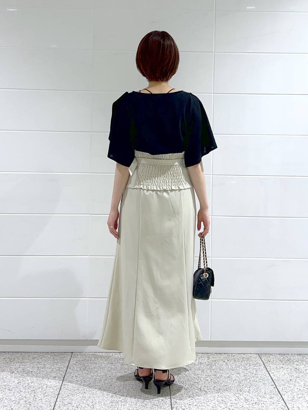 ホワイト系のスカート、ブラック系のショルダーバッグ、ブラック系のサンダルを着用したレディースの夏コーディネートの4枚目の写真