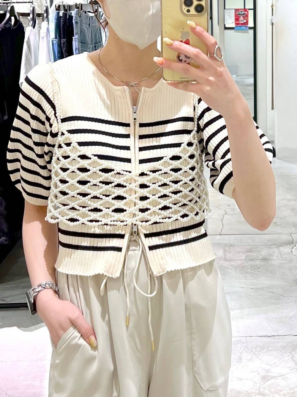 ブラック系のトートバッグ、ブラック系のサンダル、ホワイト系のベストを着用したレディースの春コーディネートの4枚目の写真