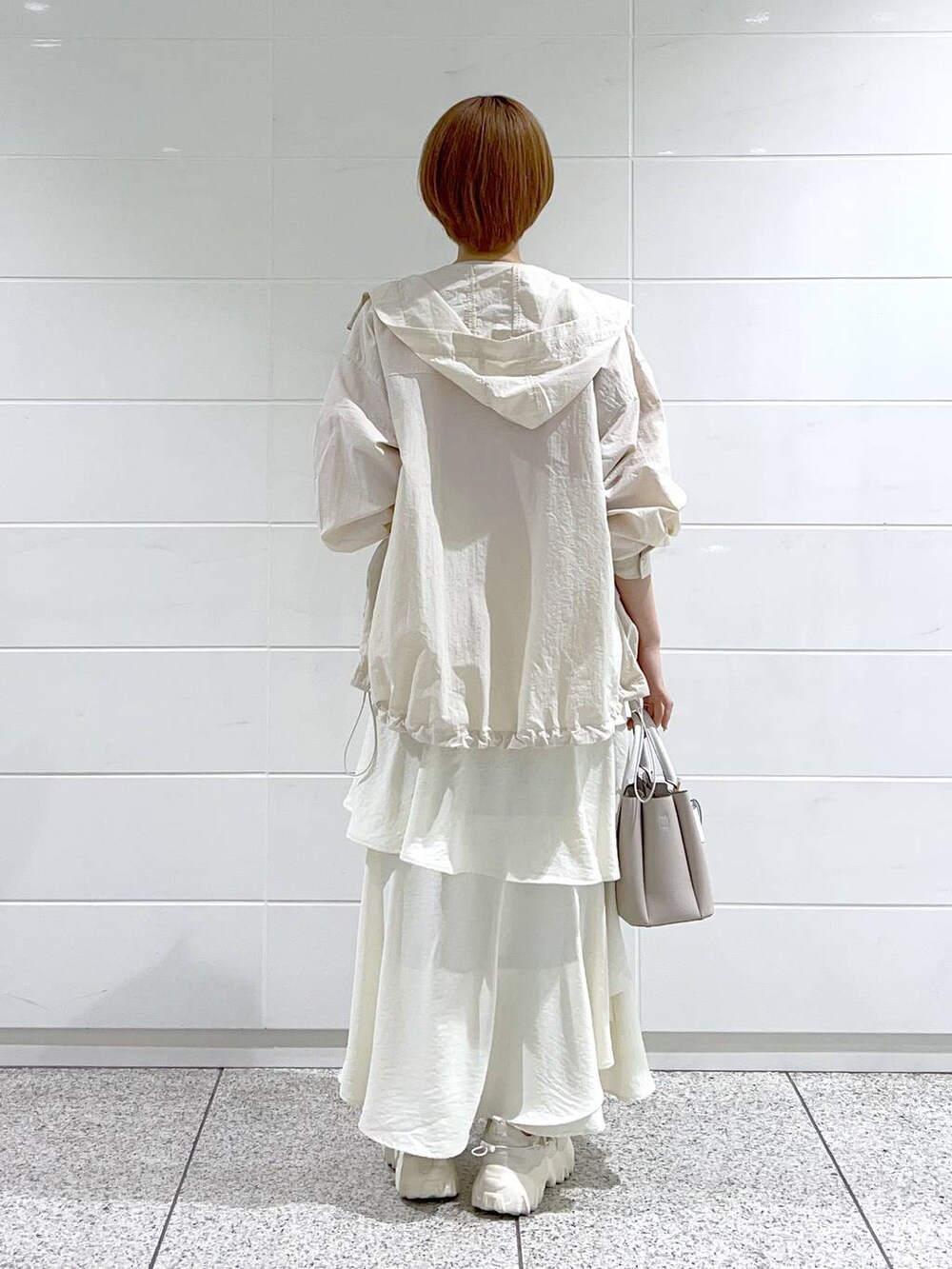 ホワイト系のスカート、ベージュ系のショルダーバッグ、ホワイト系のマウンテンパーカーを着用したレディースの春コーディネートの3枚目の写真