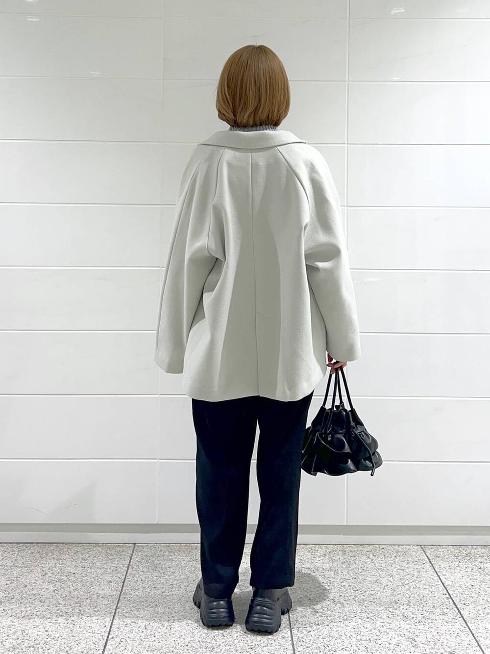 ブラック系のブーツ、ブラック系のショルダーバッグ、ホワイト系のその他アウターを着用したレディースの秋コーディネートの3枚目の写真