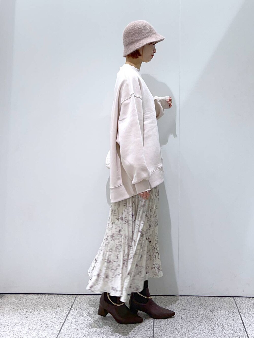 ホワイト系のショルダーバッグ、ブラウン系のブーツ、ベージュ系のスカートを着用したレディースの冬コーディネートの2枚目の写真