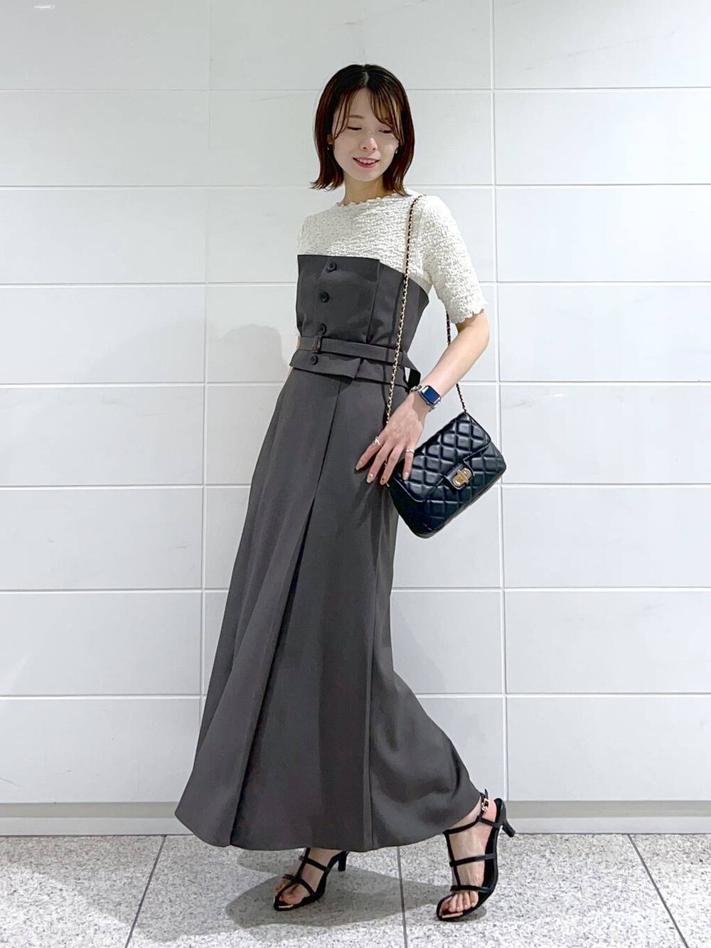 グレー系のスカート、ホワイト系のTシャツ/カットソー、ブラック系のショルダーバッグを着用したレディースの春コーディネートの2枚目の写真