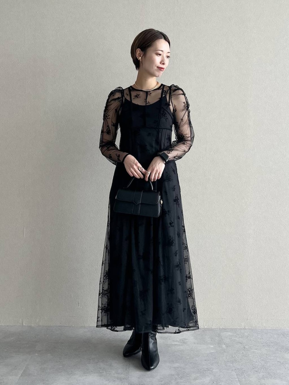 ブラック系のワンピース、パープル系のチェスターコート、ブラック系のブーツを着用したレディースの秋コーディネートの4枚目の写真