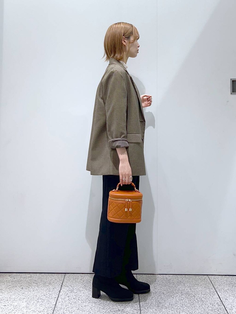 ブラック系のブーツ、ブラック系のジャンパースカート、ブラウン系のテーラードジャケットを着用したレディースの秋コーディネートの2枚目の写真