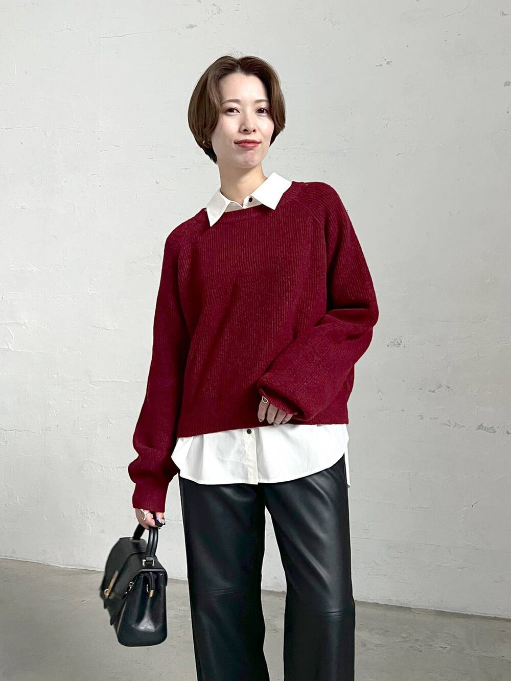 レッド系のニット/セーター、ブラック系のブーツ、ブラック系のスラックスを着用したレディースの冬コーディネートの4枚目の写真