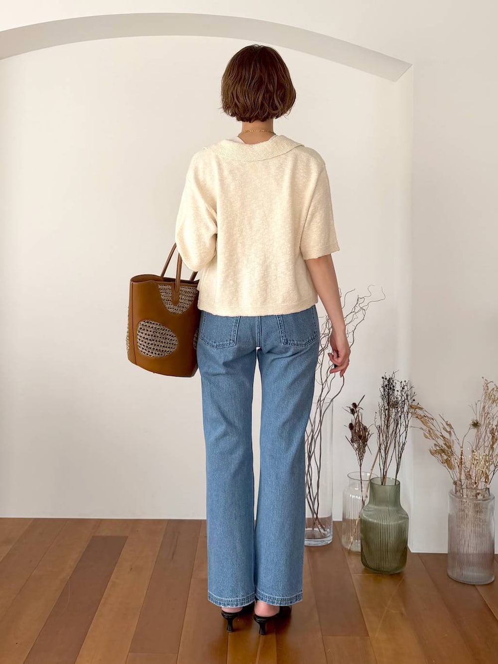 ブラウン系のトートバッグ、ブルー系のデニムパンツ、ブラック系のサンダルを着用したレディースの春コーディネートの3枚目の写真