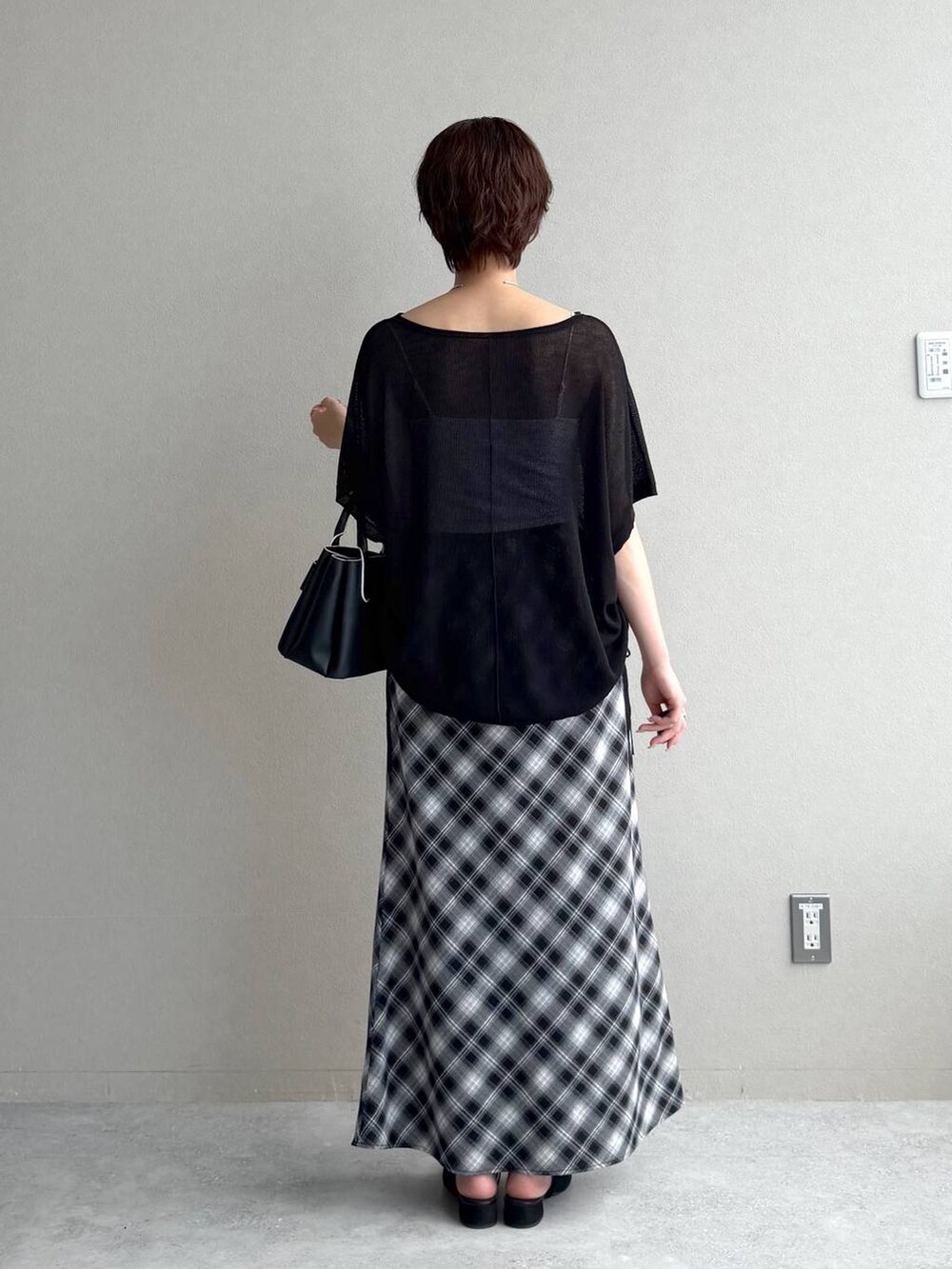 ブラック系のサンダル、グレー系のスカート、ブラック系のショルダーバッグを着用したレディースの夏コーディネートの3枚目の写真