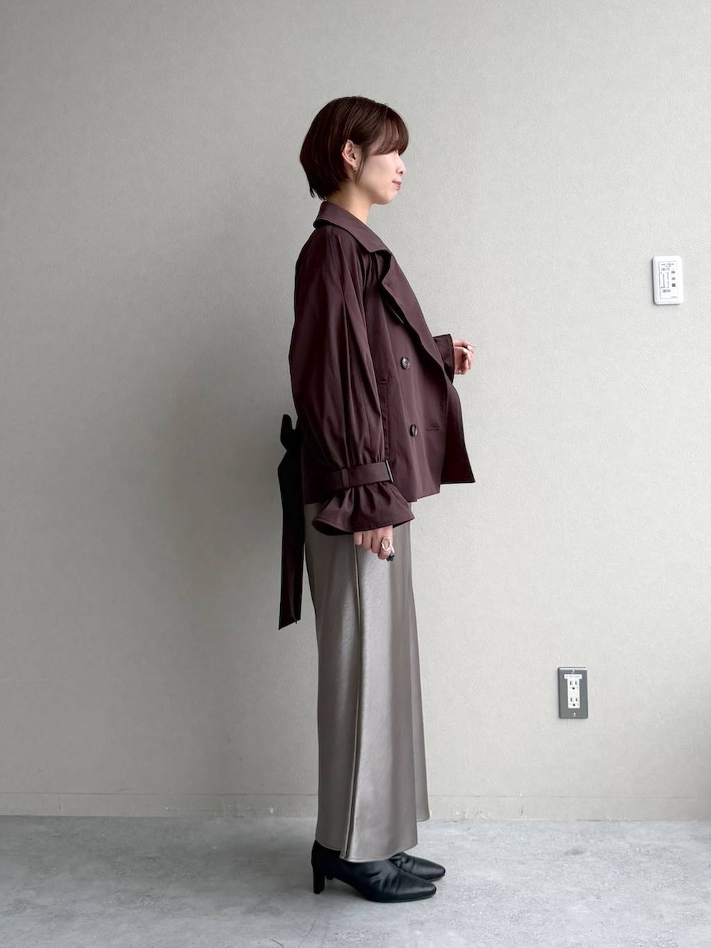 ブラック系のカーディガン/ボレロ、ブラウン系のトレンチコート、グレー系のスカートを着用したレディースの秋コーディネートの2枚目の写真