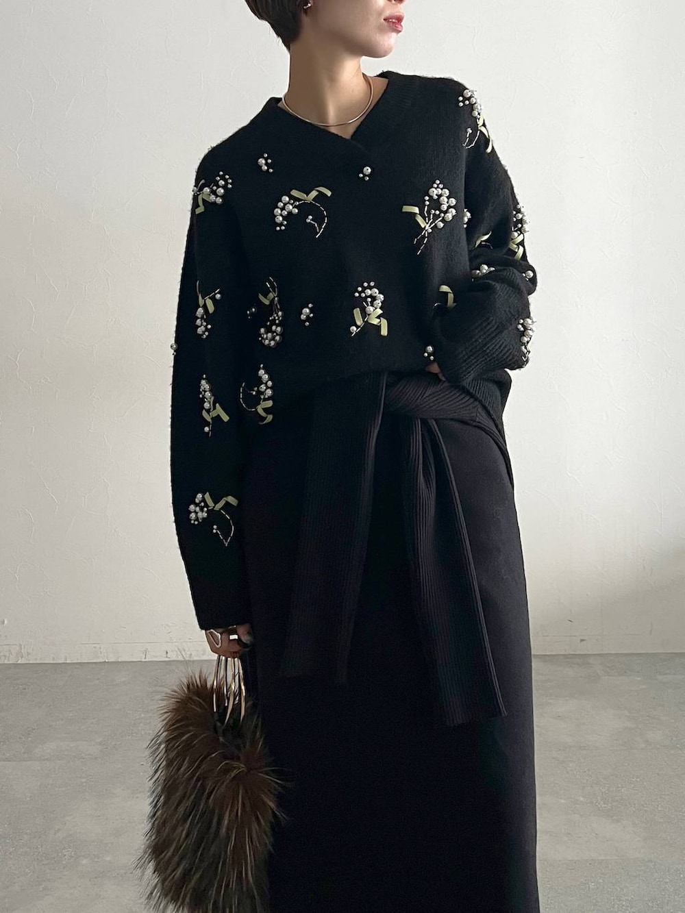 ブラック系のニット/セーター、ブルー系のデニムパンツ、ブラック系のローファーを着用したレディースの秋コーディネートの4枚目の写真