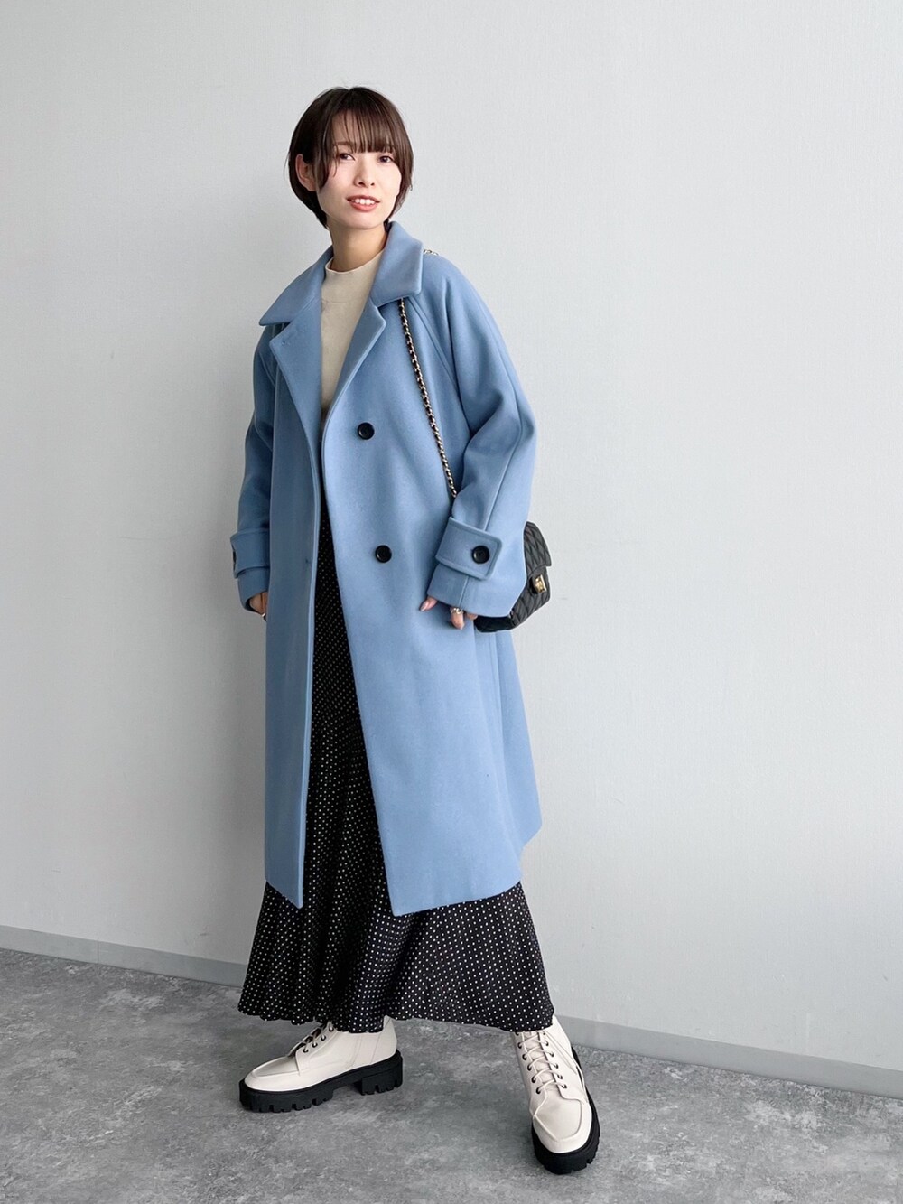 ホワイト系のニット/セーター、ブラック系のスカート、ホワイト系のブーツを着用したレディースの夏コーディネートの3枚目の写真