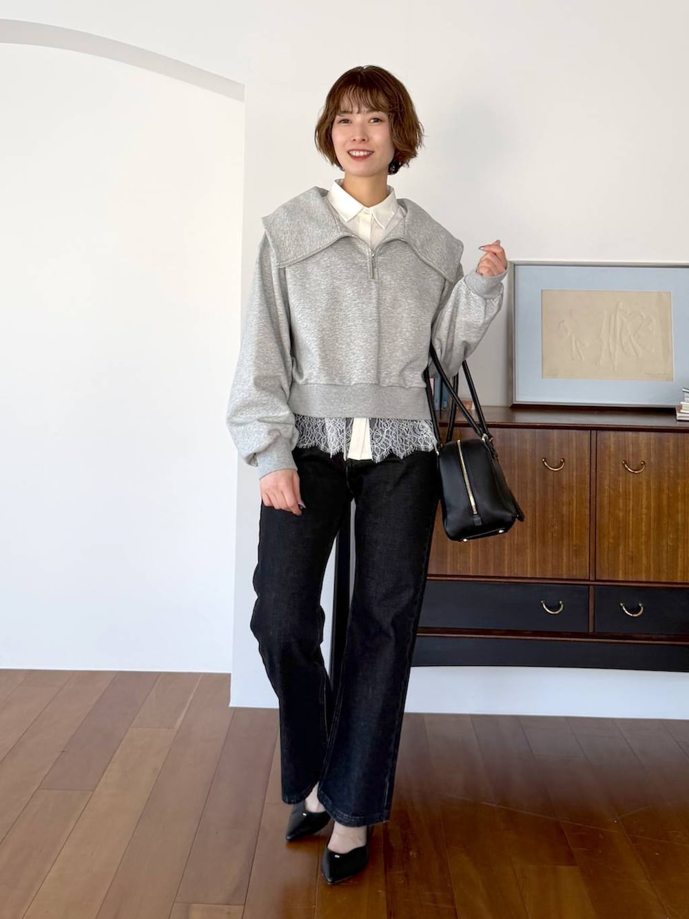 ブラック系のハンドバッグ、ブラック系のデニムパンツ、ブラック系のパンプスを着用したレディースの冬コーディネートの4枚目の写真