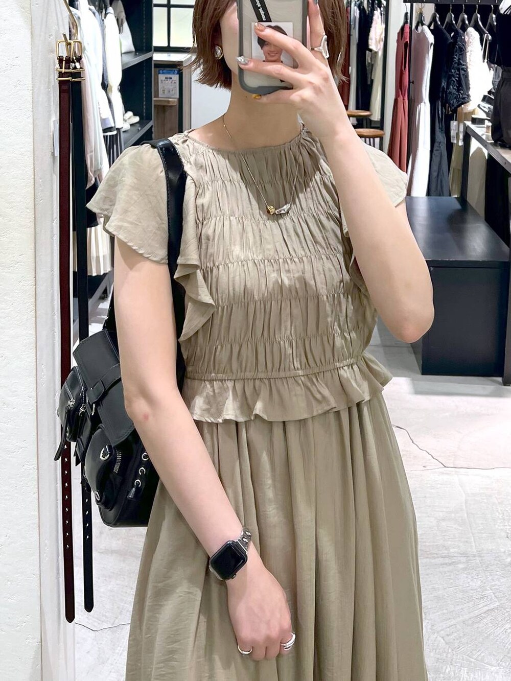 ブラック系のサンダル、ブラック系のショルダーバッグ、ベージュ系のワンピースを着用したレディースの春コーディネートの5枚目の写真