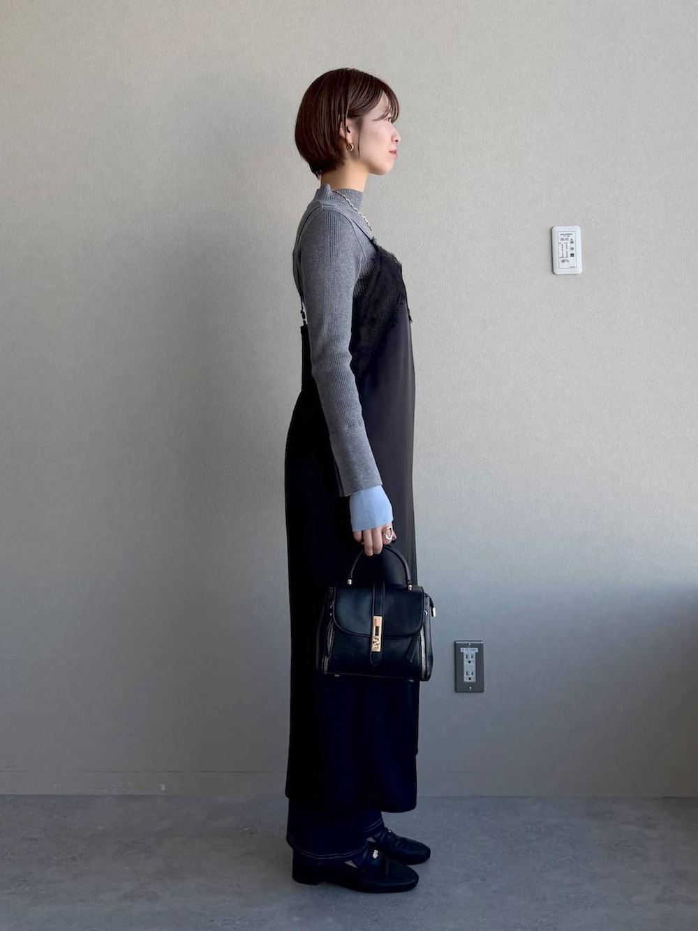 ブラック系のローファー、ブラック系のショルダーバッグ、グレー系のニット/セーターを着用したレディースの冬コーディネートの2枚目の写真