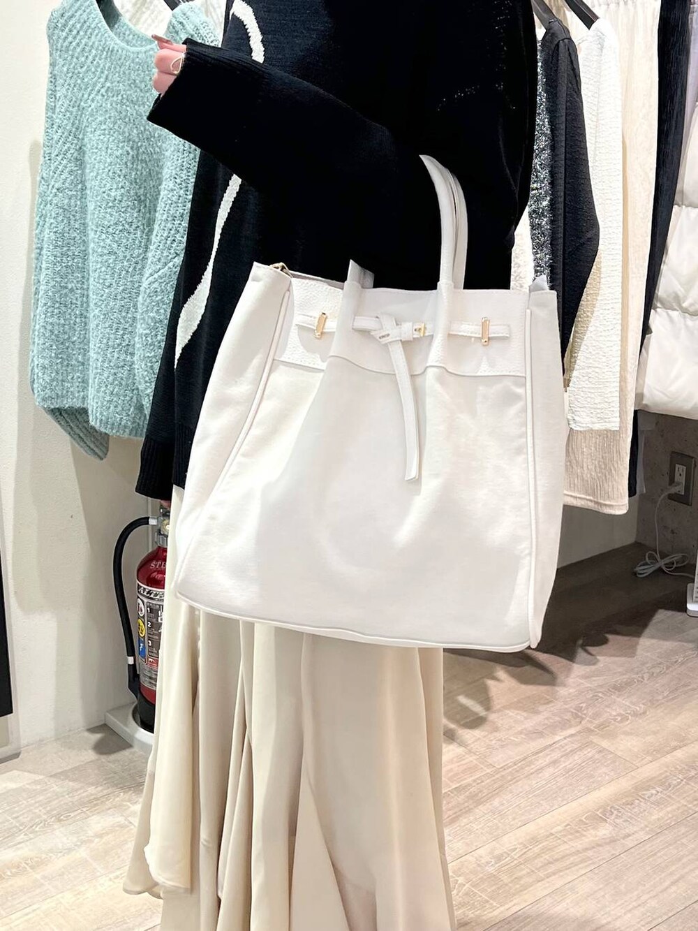 ホワイト系のトートバッグ、ブラウン系のブーツ、ベージュ系のスカートを着用したレディースの冬コーディネートの5枚目の写真