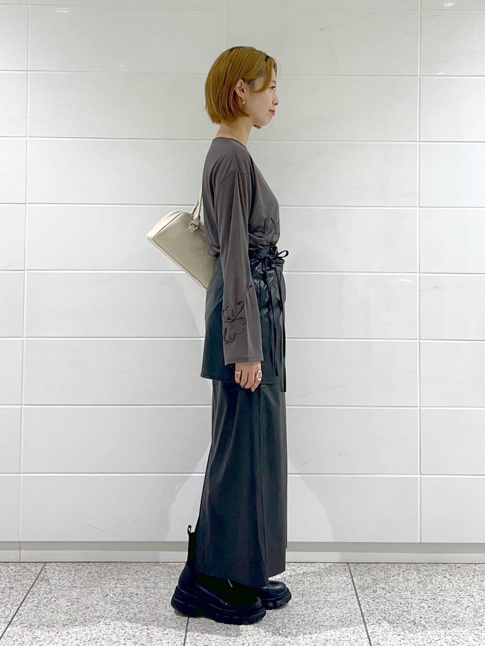 ブラック系のブーツ、グレー系のTシャツ/カットソー、ブラック系のスカートを着用したレディースの秋コーディネートの3枚目の写真