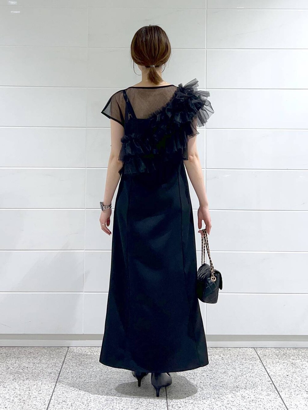 ブラック系のパンプス、ブラック系のドレス、ブラック系のショルダーバッグを着用したレディースの夏コーディネートの3枚目の写真