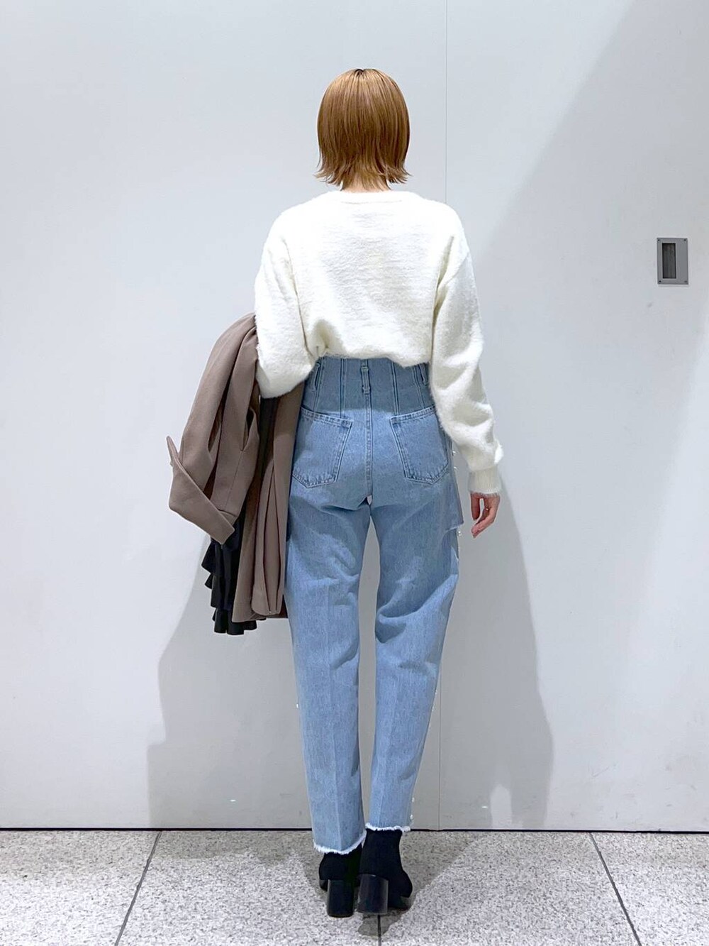 ホワイト系のニット/セーター、ブラウン系のチェスターコート、ブラック系のブーツを着用したレディースの冬コーディネートの6枚目の写真