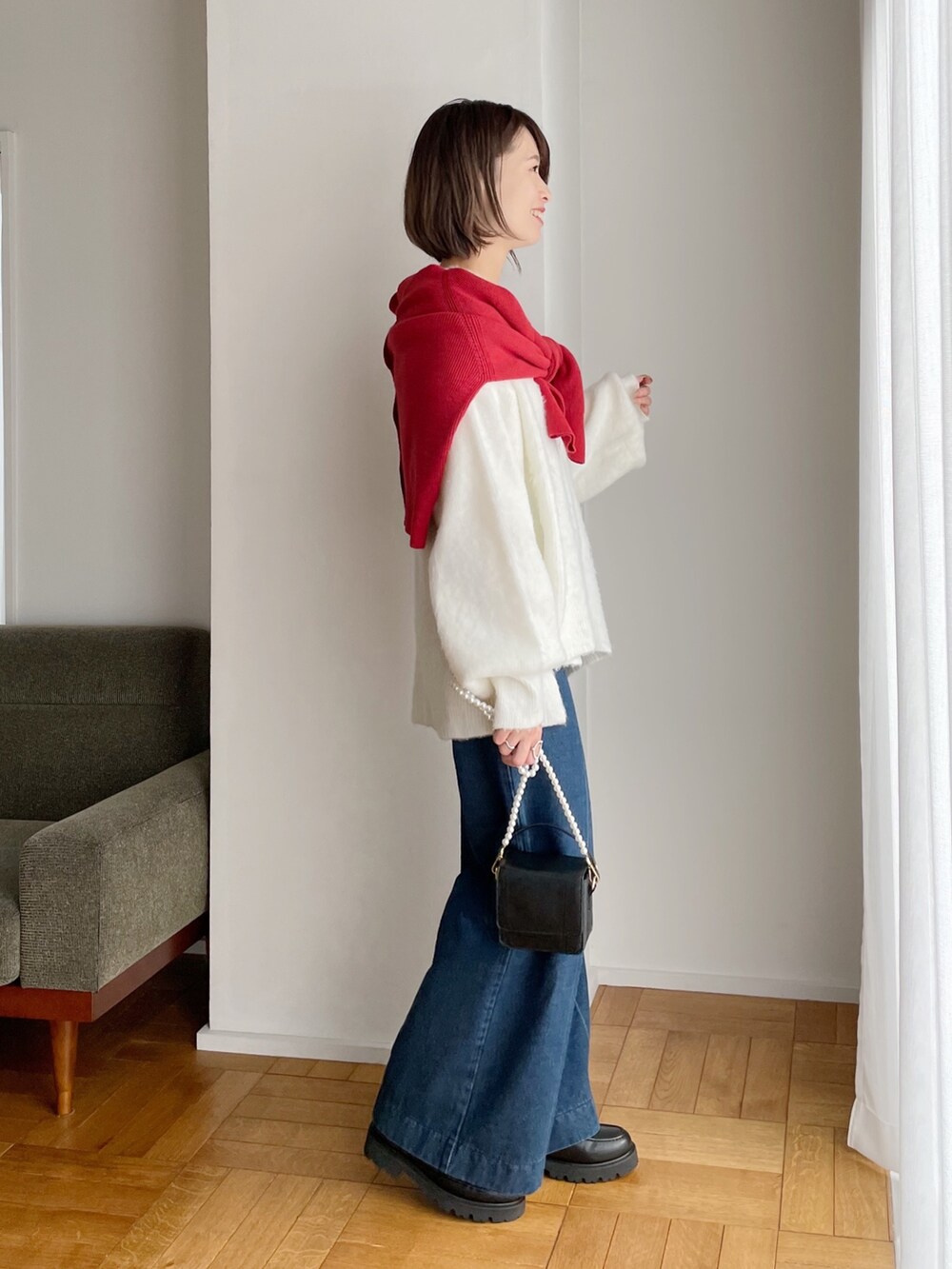 レッド系のカーディガン/ボレロ、ホワイト系のニット/セーター、ブルー系のデニムパンツを着用したレディースの冬コーディネートの2枚目の写真