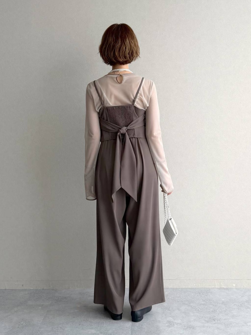 ブラック系のパンプス、ホワイト系のショルダーバッグ、ベージュ系のパンツドレスを着用したレディースの春コーディネートの4枚目の写真