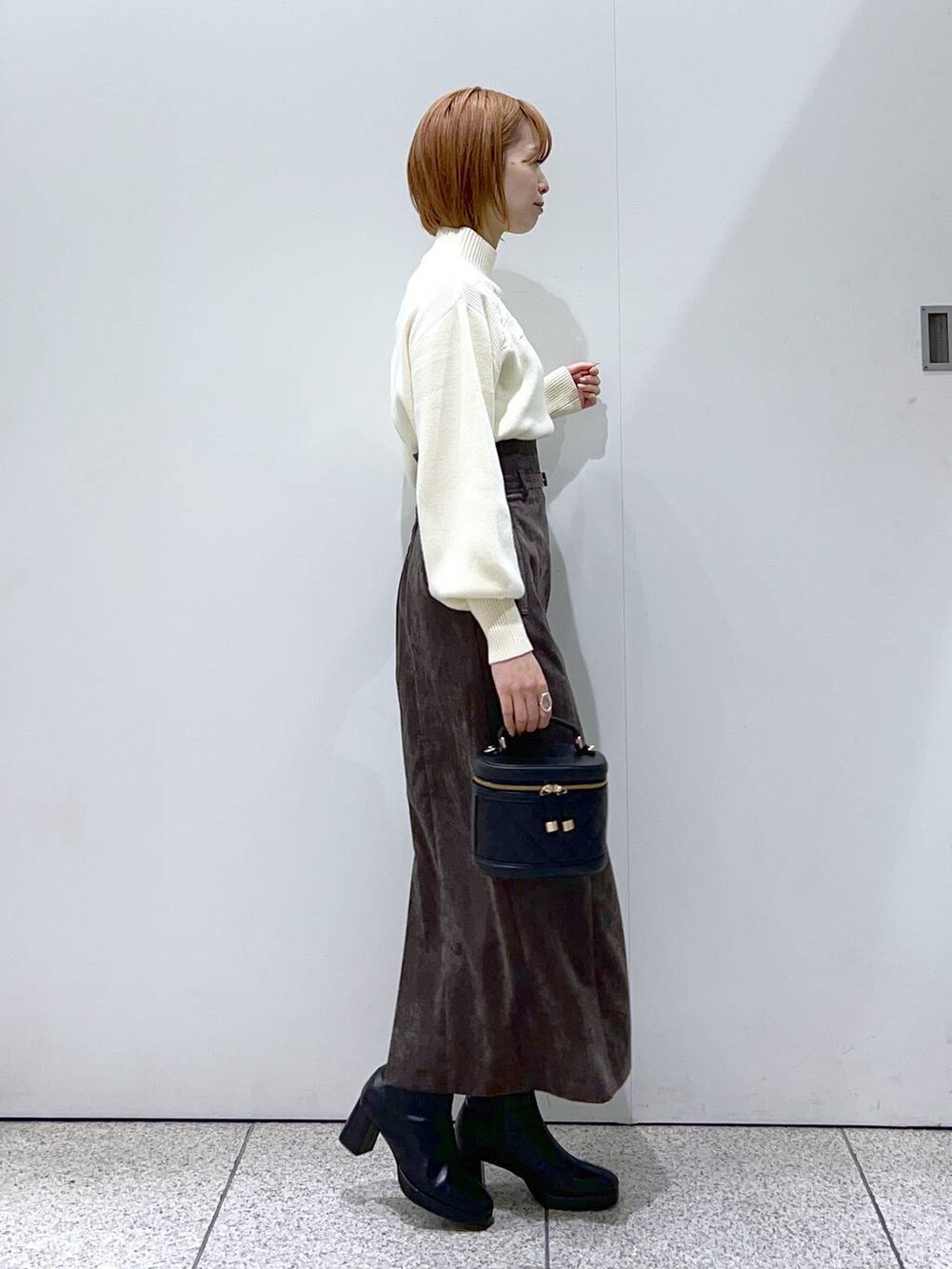 ブラウン系のスカート、ブラック系のブーツ、ブラック系のショルダーバッグを着用したレディースの冬コーディネートの5枚目の写真