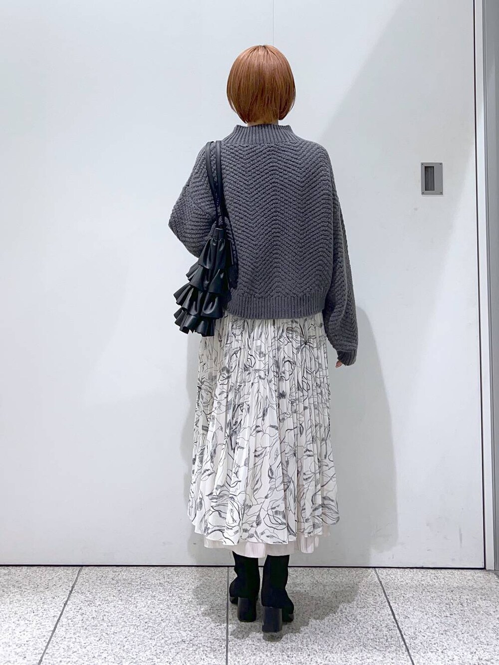 ブラック系のブーツ、ホワイト系のスカート、ブラック系のトートバッグを着用したレディースの冬コーディネートの3枚目の写真