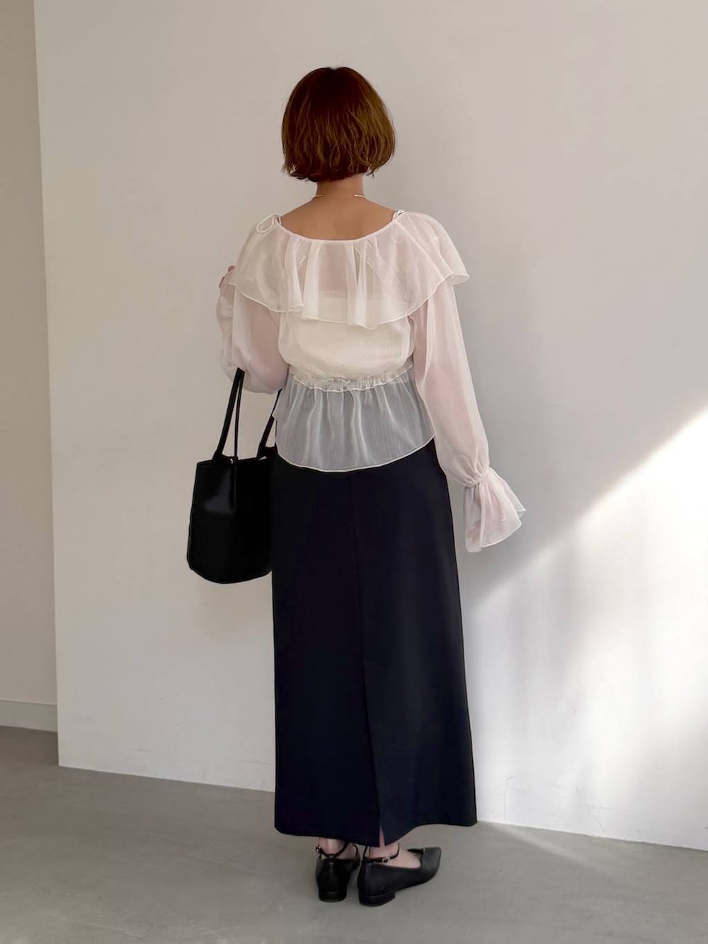 ブラック系のパンプス、ホワイト系のシャツ/ブラウス、ブルー系のスカートを着用したレディースの春コーディネートの3枚目の写真