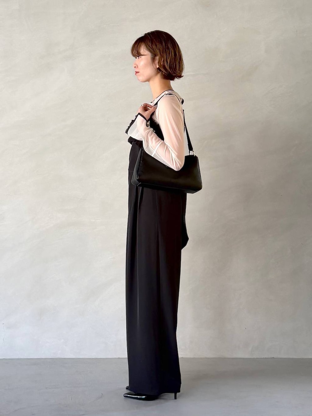 ブラック系のサンダル、ブラック系のショルダーバッグ、ブラック系のパンツドレスを着用したレディースの春コーディネートの2枚目の写真