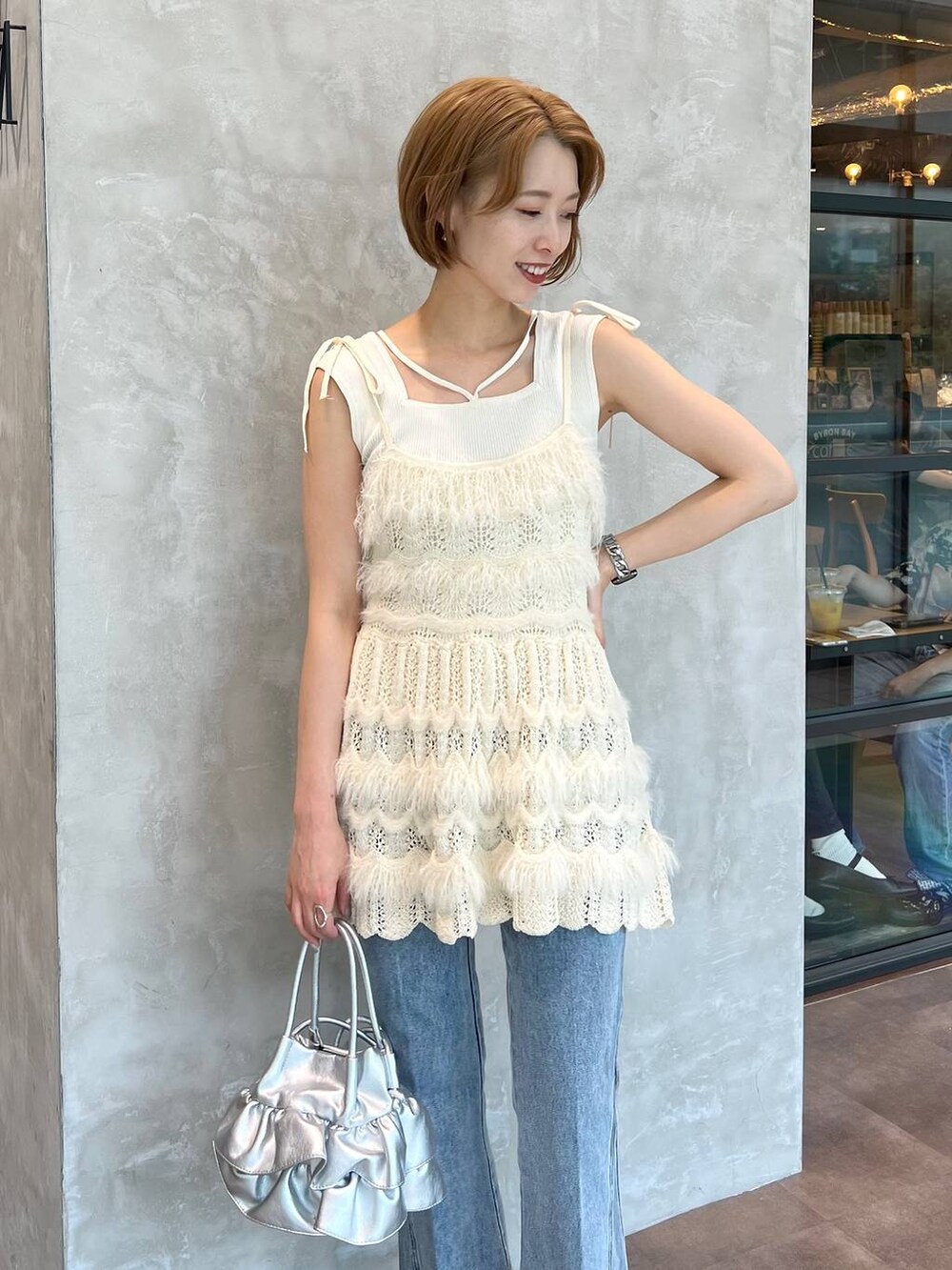 ブルー系のデニムパンツ、ホワイト系のキャミソール、ホワイト系のニット/セーターを着用したレディースの秋コーディネートの4枚目の写真