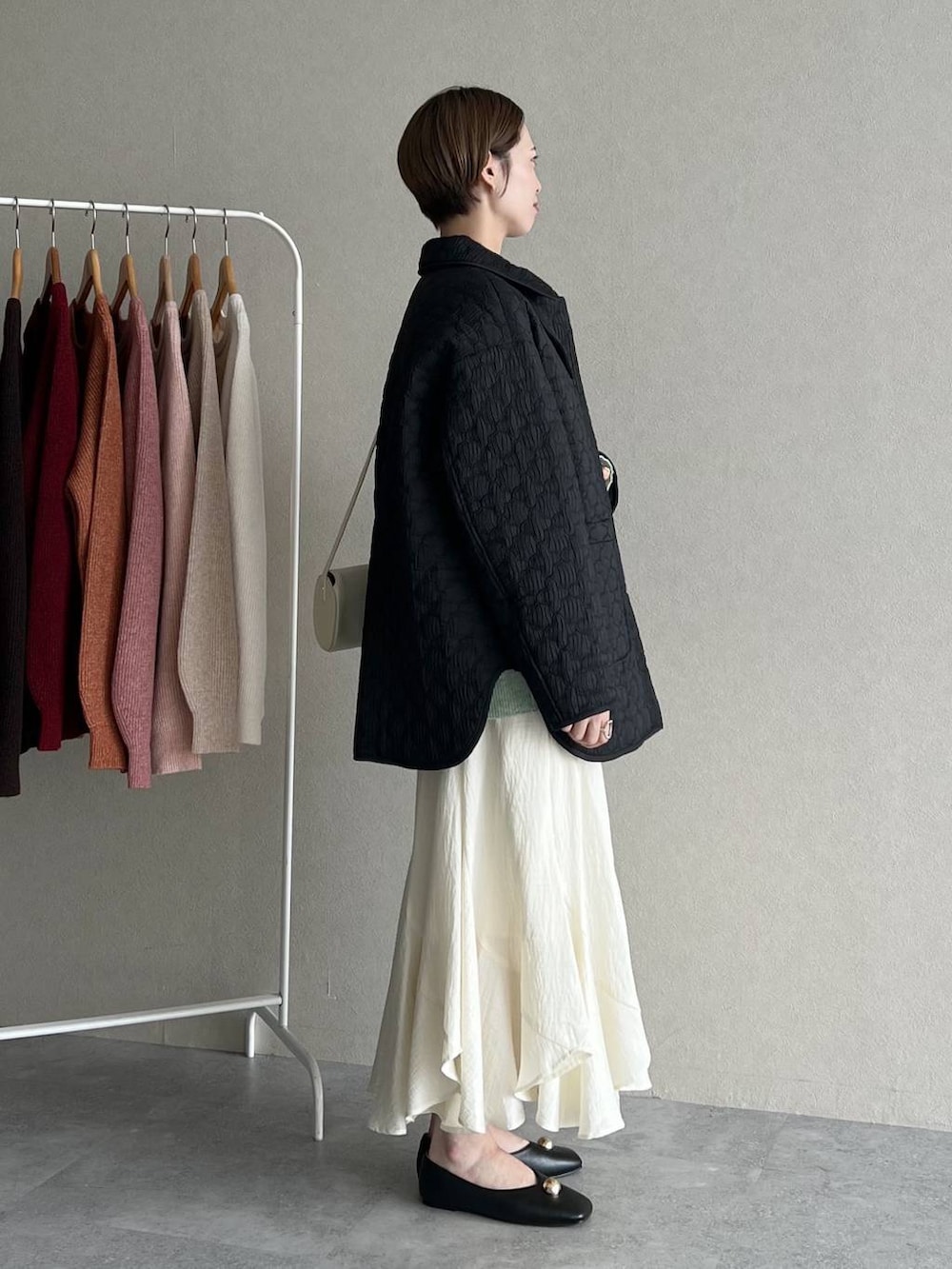 ホワイト系のスカート、ブラック系のブルゾン、ホワイト系のショルダーバッグを着用したレディースの秋コーディネートの2枚目の写真