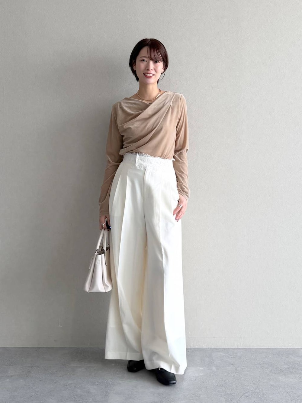 ベージュ系のトレンチコート、ベージュ系のTシャツ/カットソー、ホワイト系のスラックスを着用したレディースの秋コーディネートの5枚目の写真