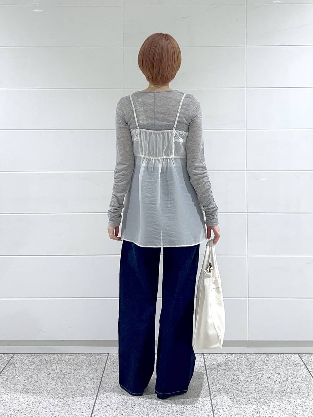 ホワイト系のトートバッグ、ブルー系のデニムパンツ、ブラック系のバレエシューズを着用したレディースの冬コーディネートの3枚目の写真