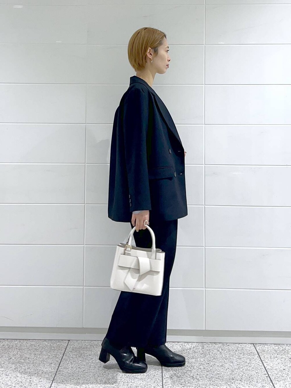 グレー系のTシャツ/カットソー、ブラック系のブーツ、ホワイト系のショルダーバッグを着用したレディースの冬コーディネートの2枚目の写真