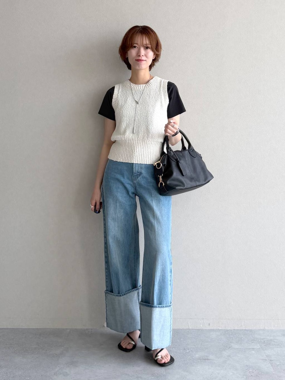 ブラック系のボストンバッグ、ブルー系のデニムパンツ、ホワイト系のベストを着用したレディースの夏コーディネートの5枚目の写真