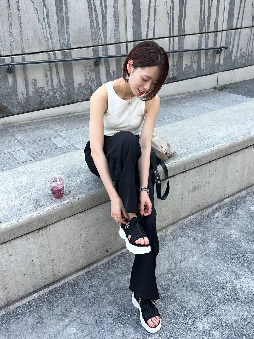 ブラック系のサンダル、ブラック系のスラックス、ブラック系のショルダーバッグを着用したレディースの夏コーディネートの2枚目の写真