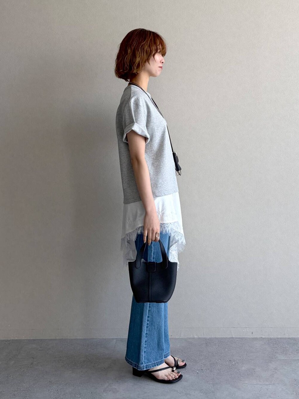 ブルー系のデニムパンツ、グレー系のTシャツ/カットソー、ブラック系のショルダーバッグを着用したレディースの春コーディネートの2枚目の写真