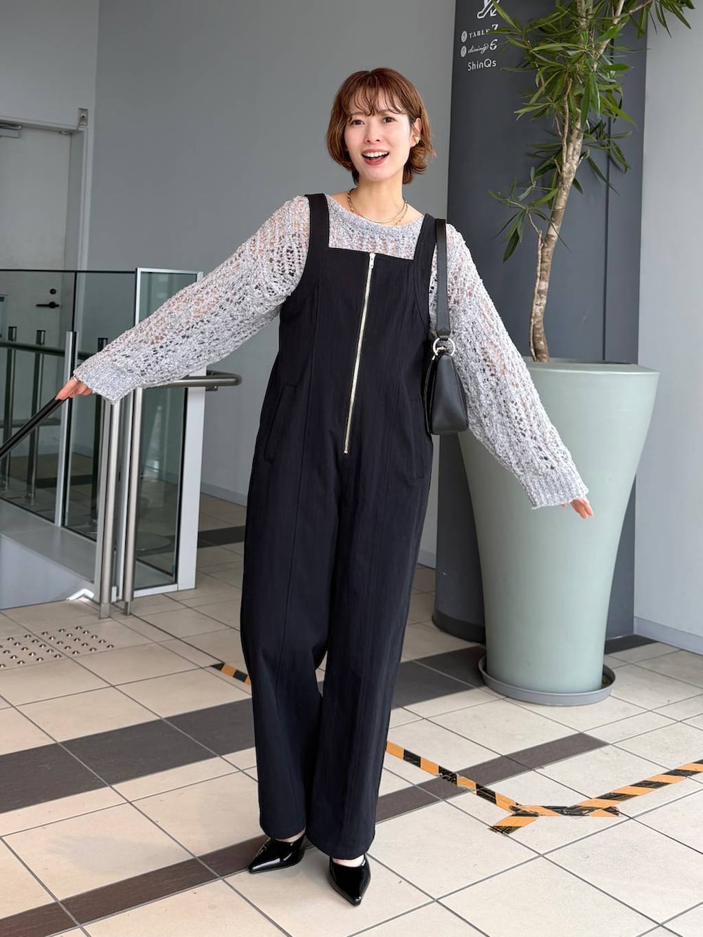 グレー系のニット/セーター、ブラック系のサンダル、ブラック系のショルダーバッグを着用したレディースの春コーディネートの5枚目の写真