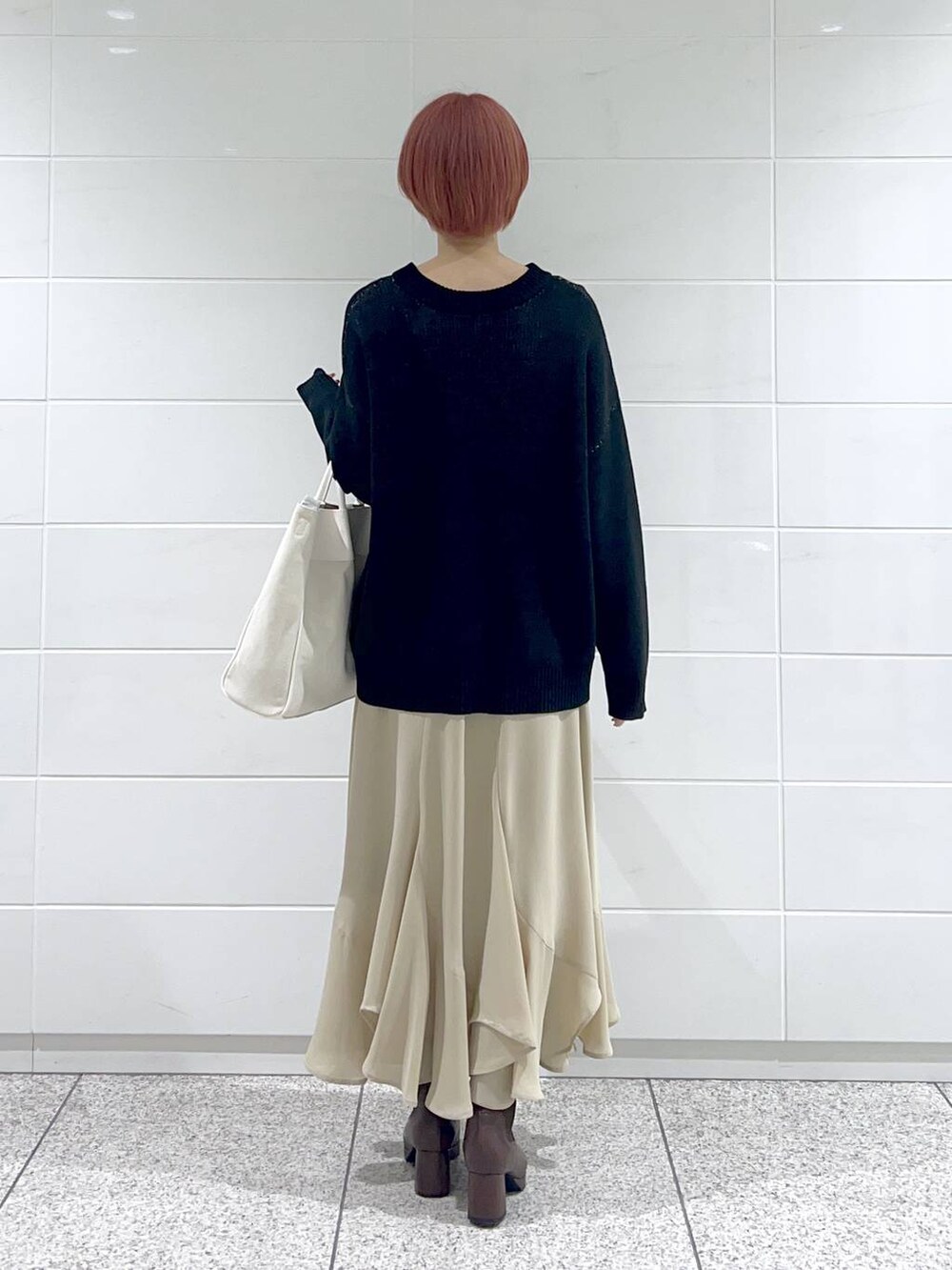 ホワイト系のトートバッグ、ブラウン系のブーツ、ベージュ系のスカートを着用したレディースの冬コーディネートの3枚目の写真