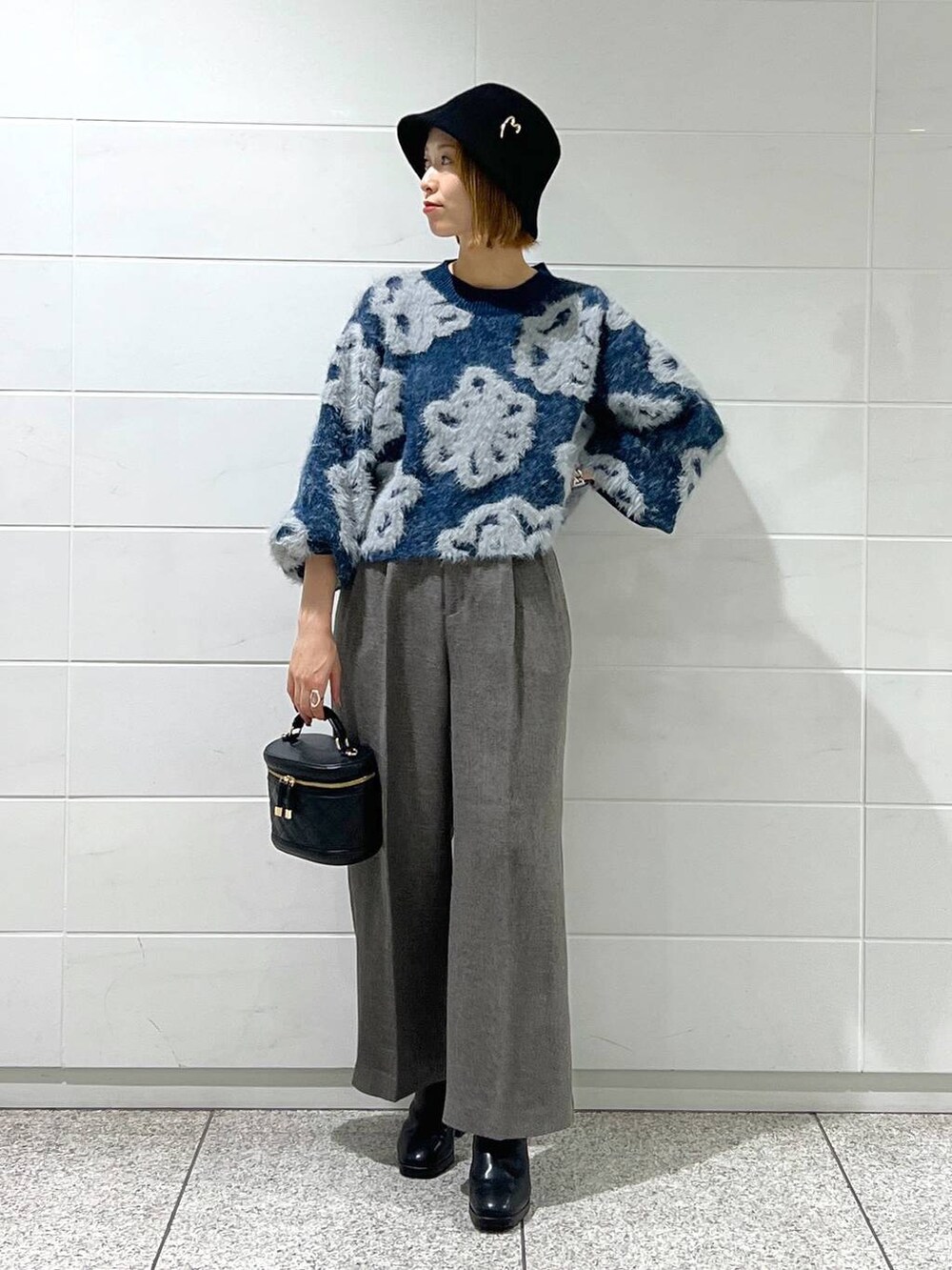 ブルー系のニット/セーター、ブラック系のショルダーバッグ、ブラック系のブーツを着用したレディースの秋コーディネートの2枚目の写真