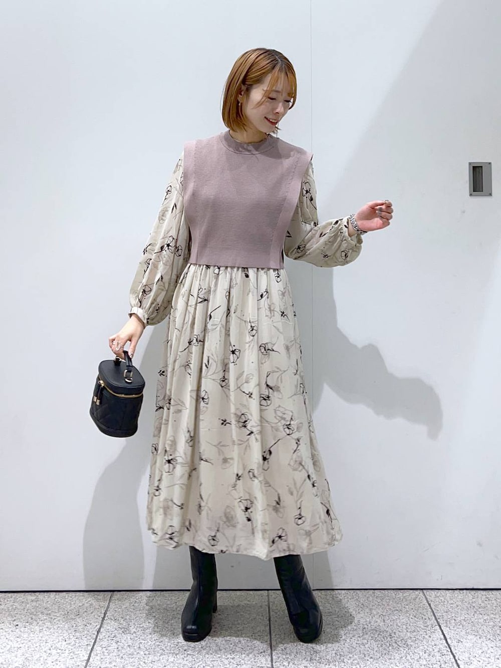 ブルー系のノーカラーコート、ブラック系のブーツ、ベージュ系のワンピースを着用したレディースの秋コーディネートの4枚目の写真