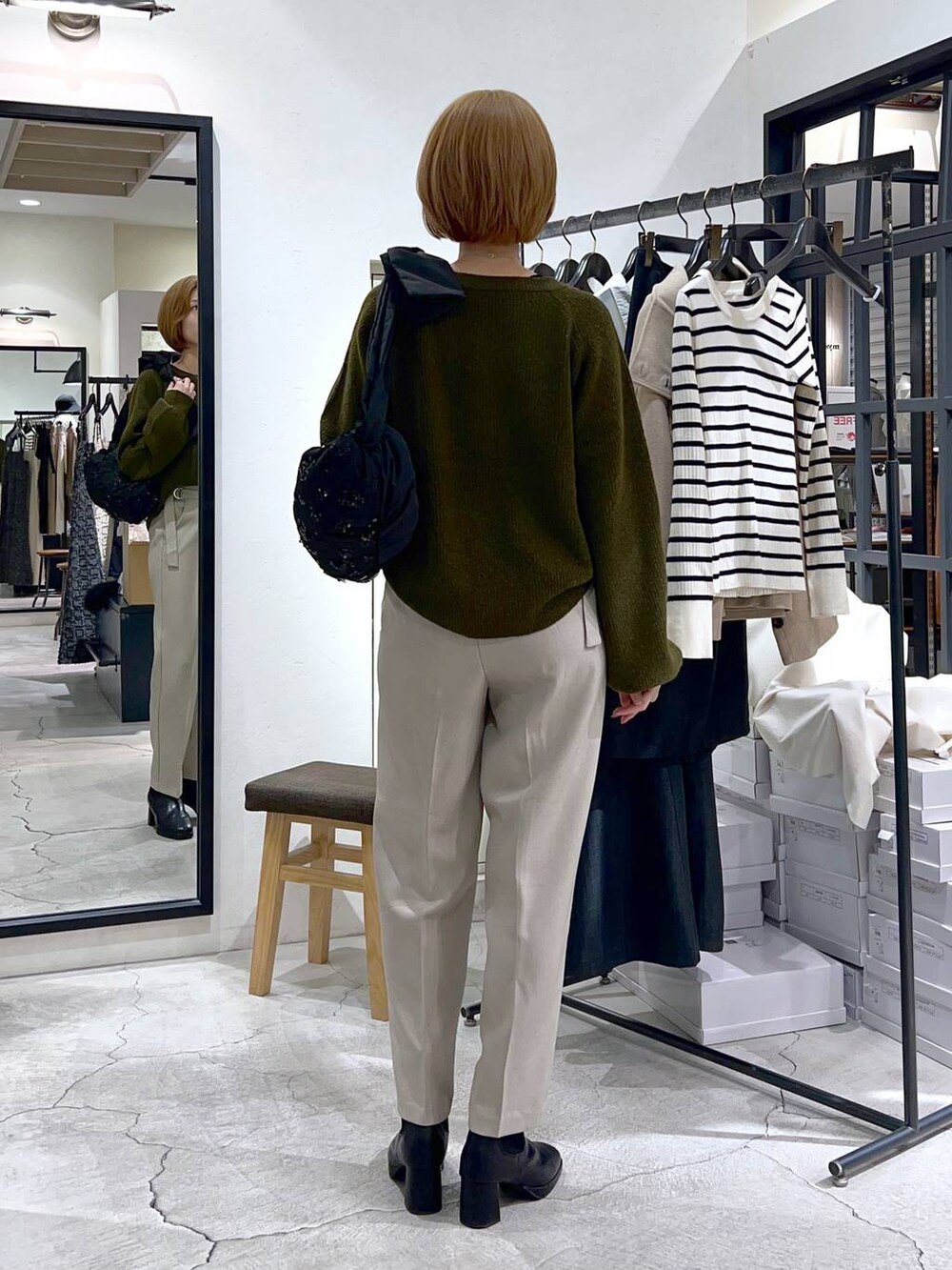 ブラック系のショルダーバッグ、ブラック系のブーツ、グリーン系のニット/セーターを着用したレディースの秋コーディネートの3枚目の写真