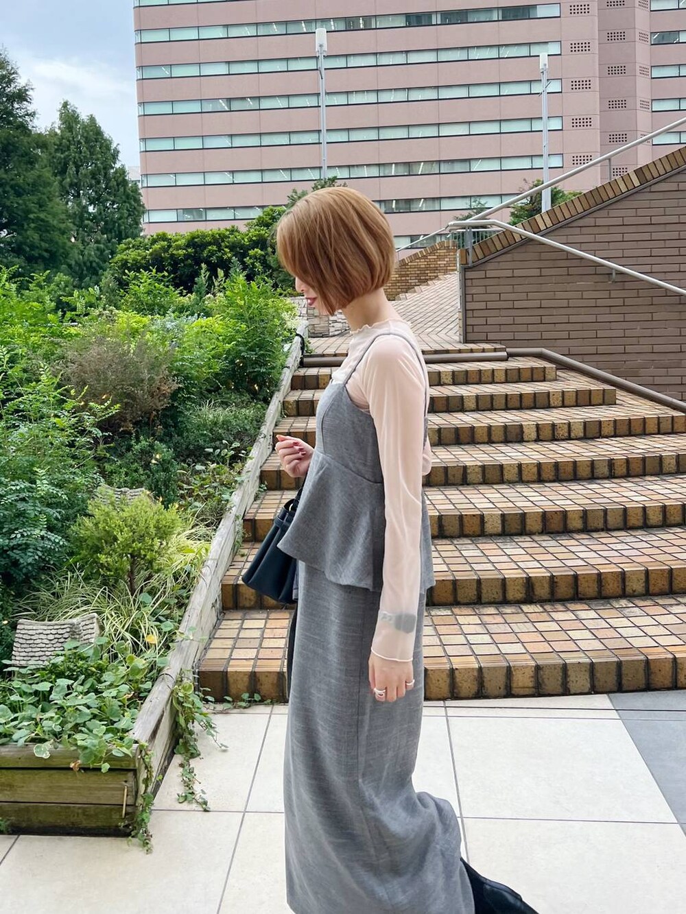 ブラック系のショルダーバッグ、ホワイト系のキャミソール、ブラック系のブーツを着用したレディースの秋コーディネートの3枚目の写真