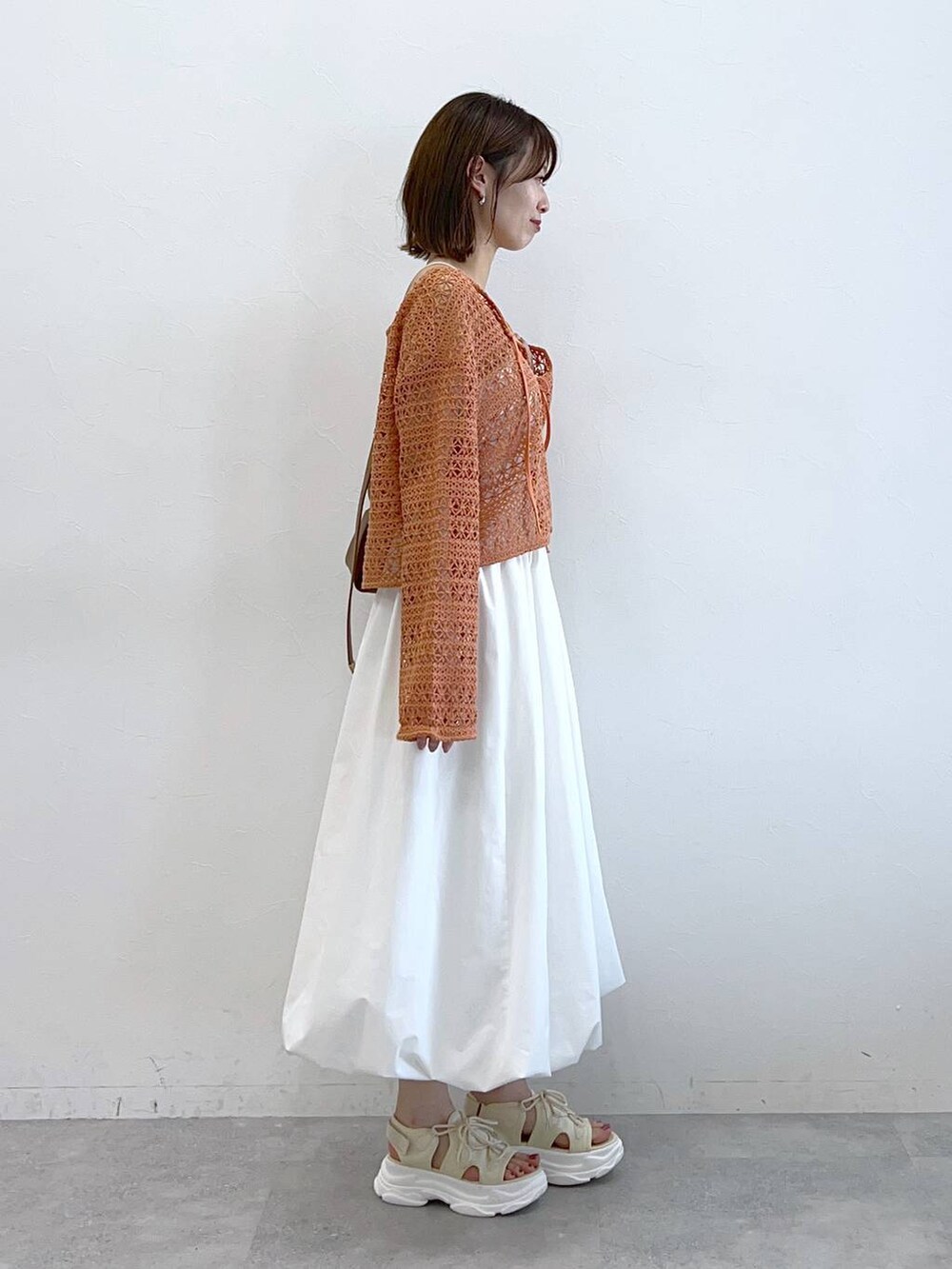ホワイト系のサンダル、オレンジ系のカーディガン/ボレロ、ホワイト系のキャミソールを着用したレディースの春コーディネートの2枚目の写真