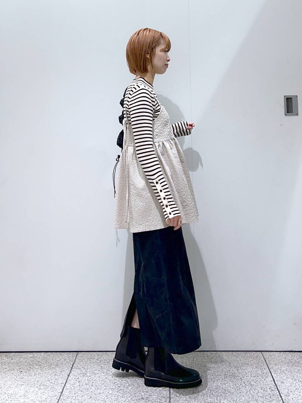 ブラック系のスカート、ベージュ系のキャミソール、ブラック系のハンドバッグを着用したレディースの冬コーディネートの2枚目の写真