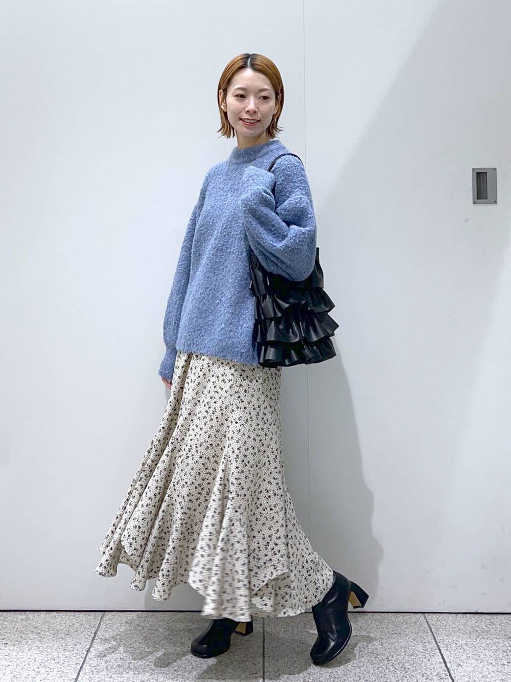 ブラック系のブーツ、ブルー系のニット/セーター、ホワイト系のスカートを着用したレディースの冬コーディネートの5枚目の写真