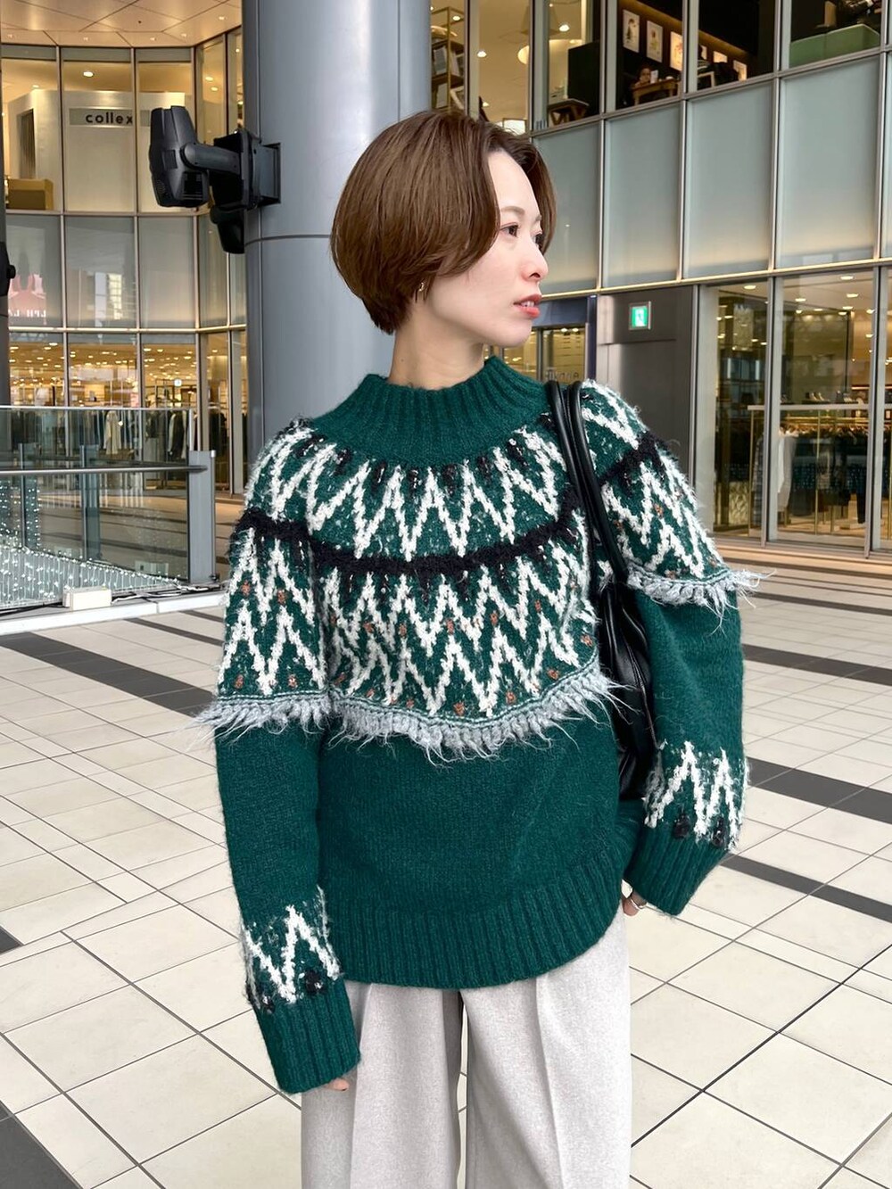 ブラック系のトートバッグ、ブラック系のブーツ、グリーン系のニット/セーターを着用したレディースの秋コーディネートの4枚目の写真