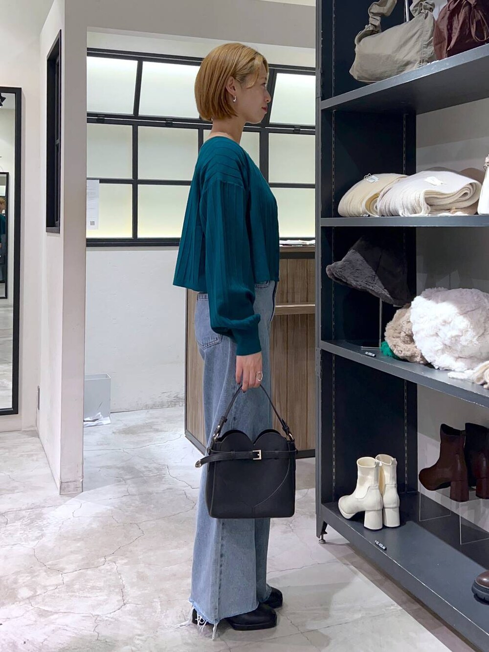 ブルー系のデニムパンツ、ブラック系のショルダーバッグ、ブラック系のブーツを着用したレディースの秋コーディネートの2枚目の写真