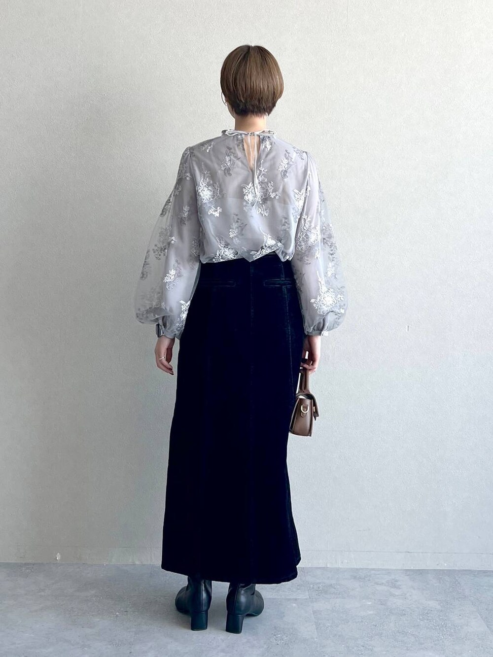 グレー系のシャツ/ブラウス、ブラック系のスカート、ブラック系のブーツを着用したレディースの秋コーディネートの3枚目の写真